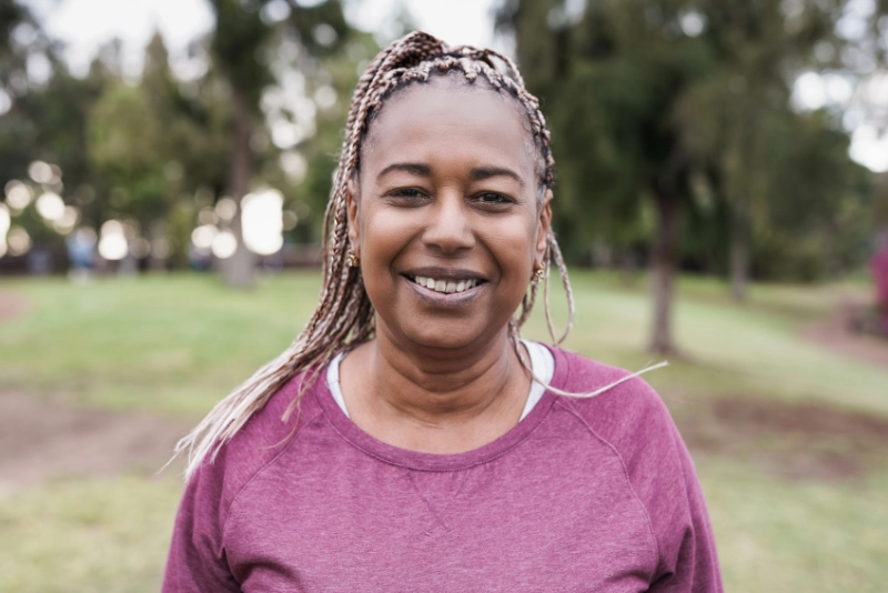 Smiling woman standing outdoors in a public park.